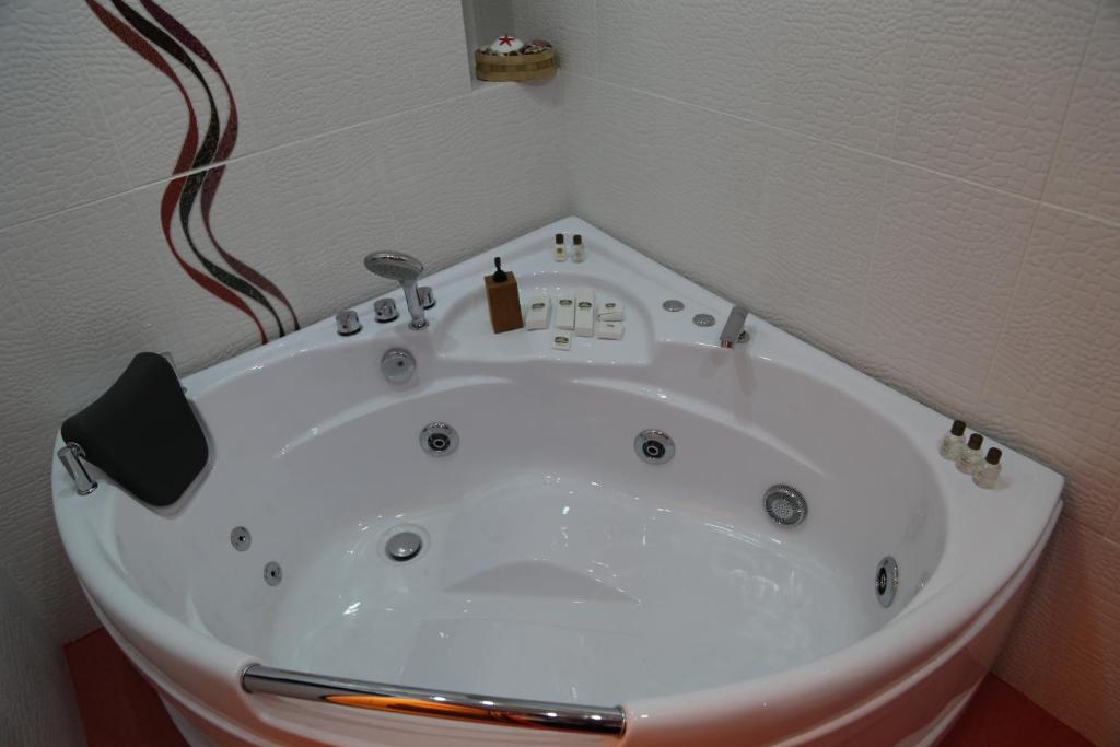 a white bath tub in a bathroom with a shower at Versace Downtown Yerevan in Yerevan