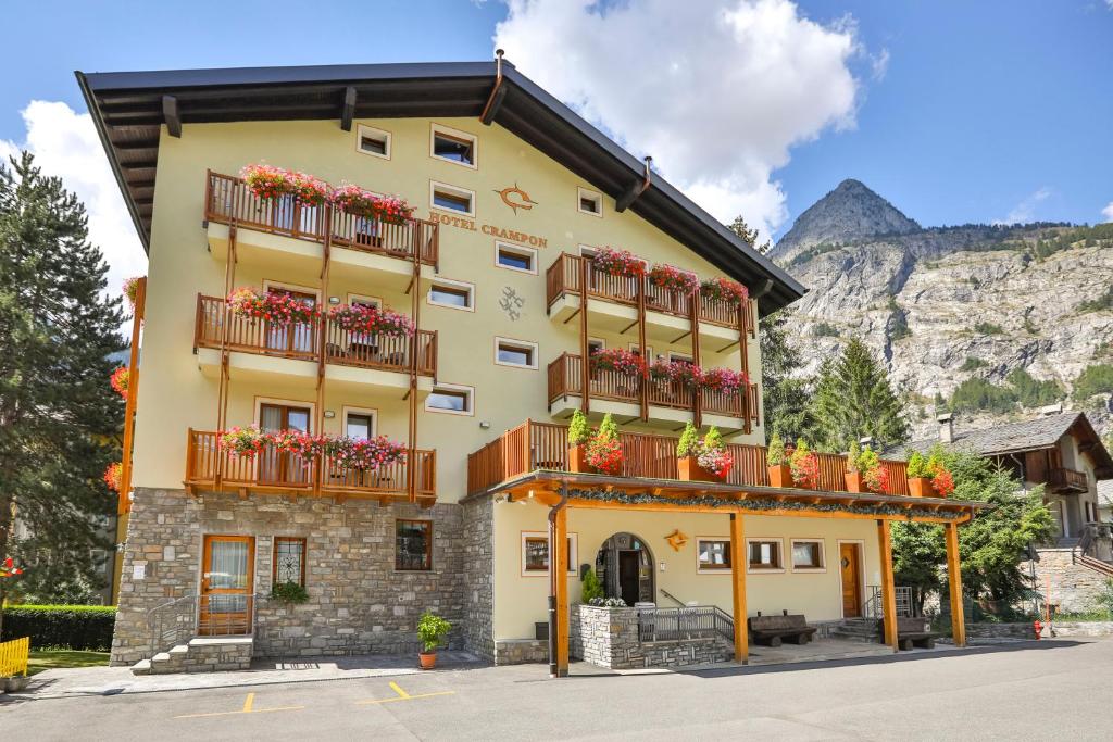 un edificio giallo con balconi e fiori di Hotel Crampon a Courmayeur