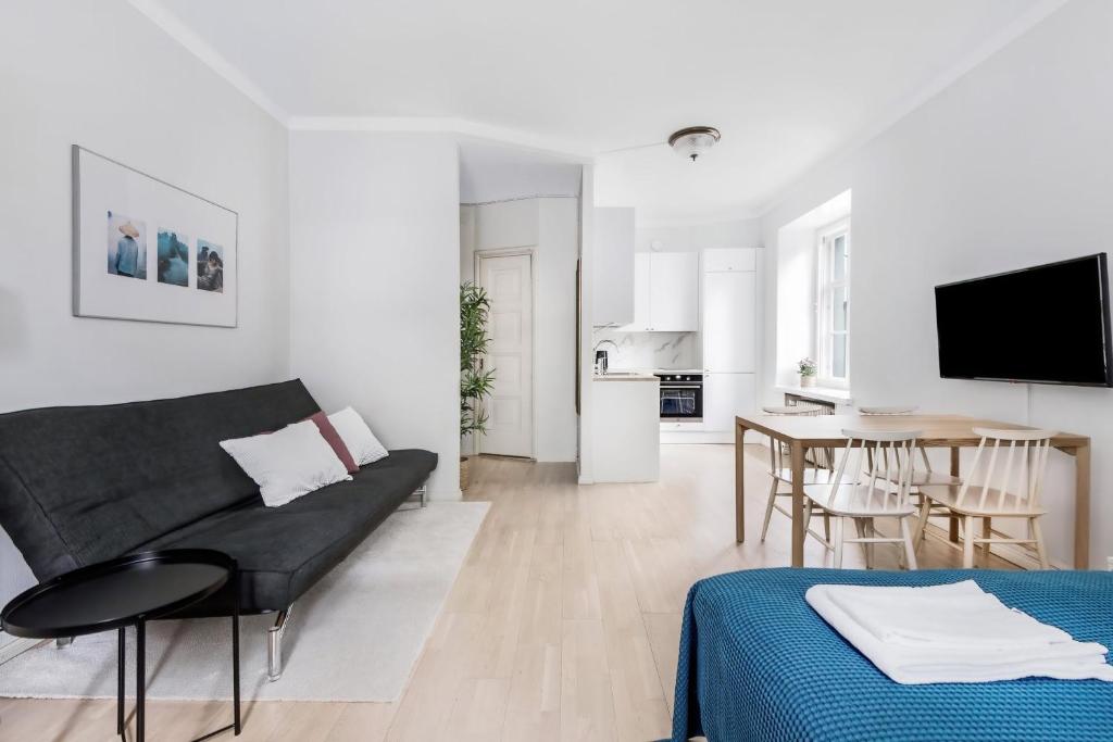 een witte woonkamer met een bank en een tafel bij WeHost Modern Scandinavian Studio in Trendy Kallio in Helsinki