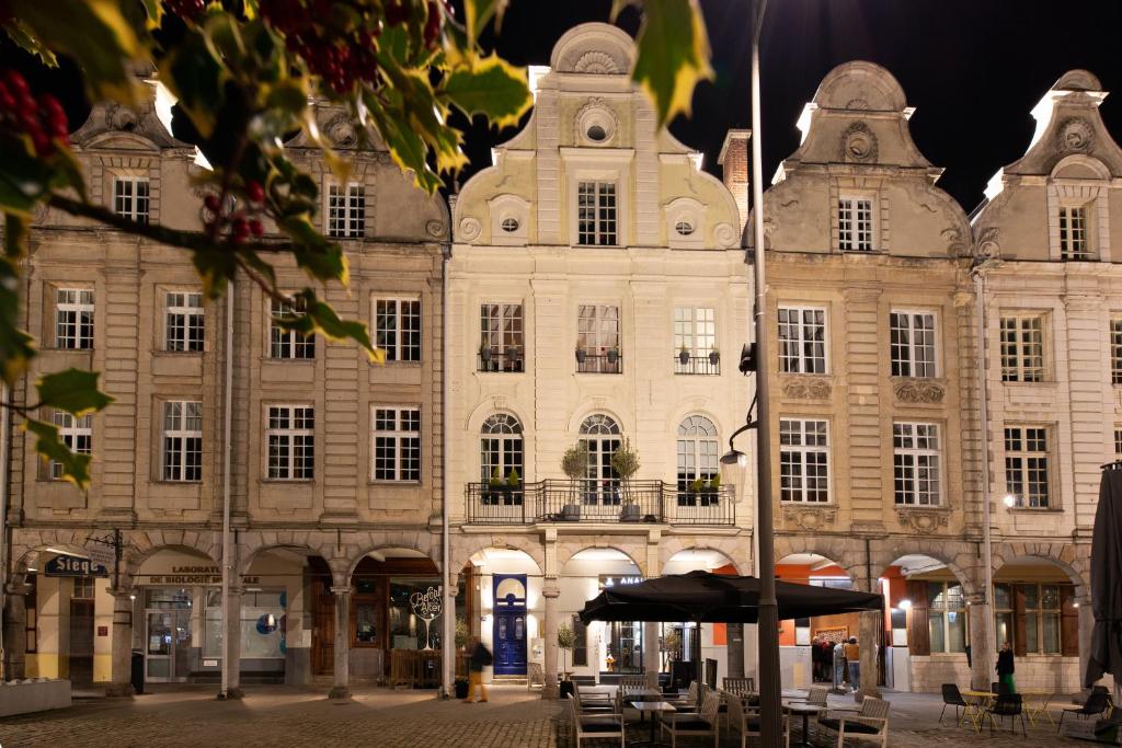 un grand bâtiment avec un parasol devant lui dans l'établissement Grand Place Hôtel "Boutique et Appart'hôtel", à Arras