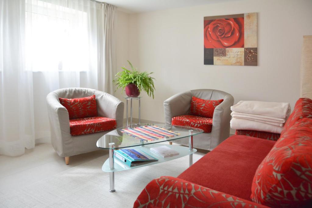 sala de estar con 2 sillas y sofá rojo en Ferienwohnung Gohrisch en Kurort Gohrisch