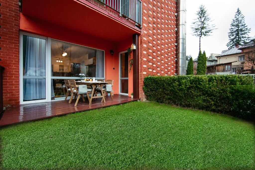 una casa con terraza con mesa y césped en Home & Garden with stunning view en Sinaia