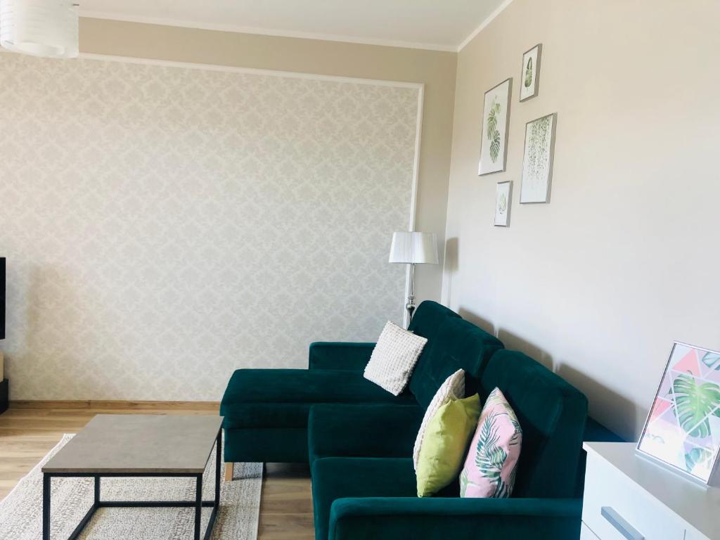 ein Wohnzimmer mit einem grünen Sofa und einem Tisch in der Unterkunft Apartament słoneczny in Olsztyn
