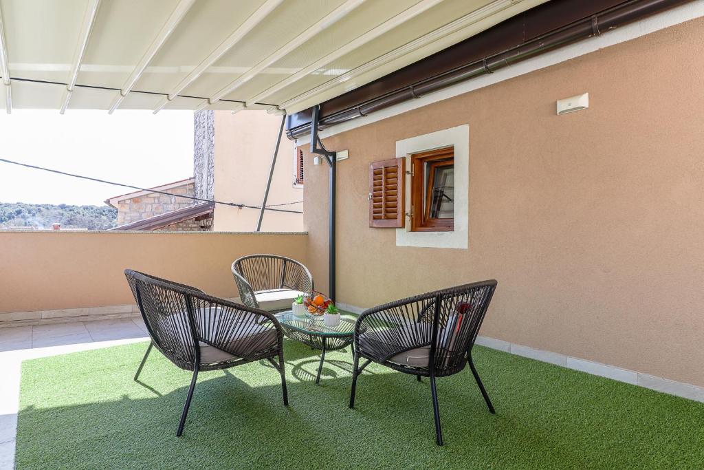 eine Terrasse mit 3 Stühlen, einem Tisch und einem Fenster in der Unterkunft Apartman Juraj i Matej in Vrsar
