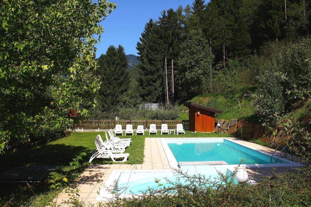 a backyard with a pool and chairs and a house at Casa Ornella in Ledro