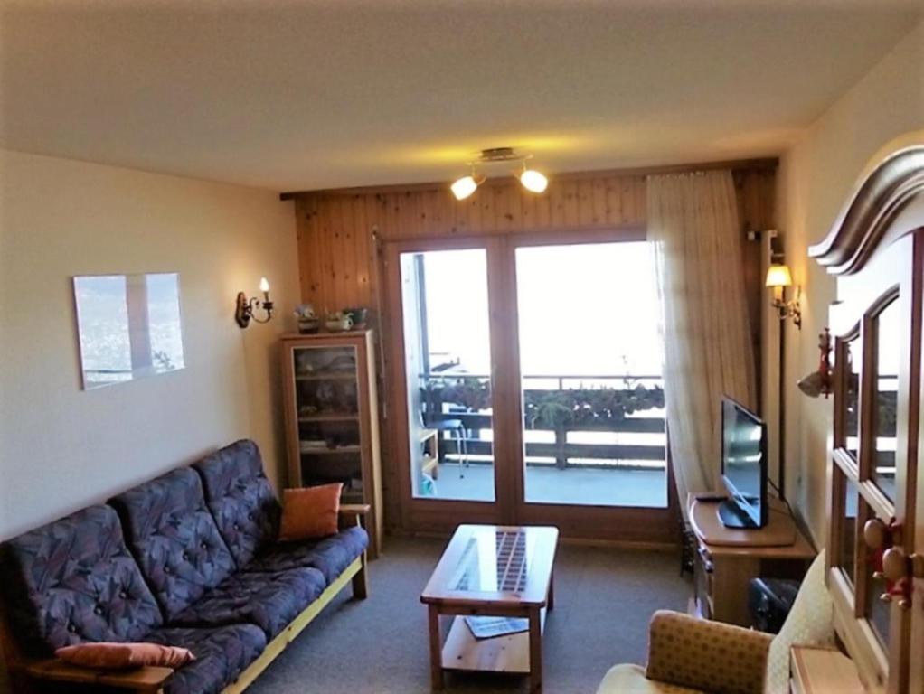 uma sala de estar com um sofá, uma mesa e uma janela em Fontanettaz MOUNTAIN & COSY apartments by Alpvision Résidences em Veysonnaz