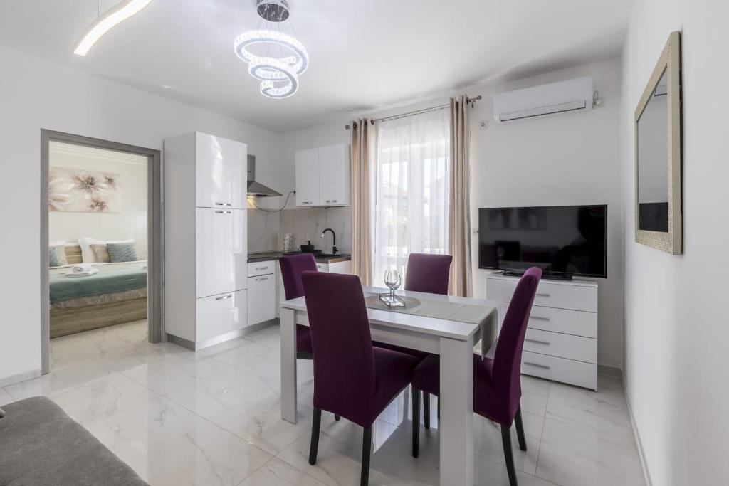 eine Küche und ein Esszimmer mit einem Tisch und lila Stühlen in der Unterkunft Royal Rose Gold Apartment in Vodice