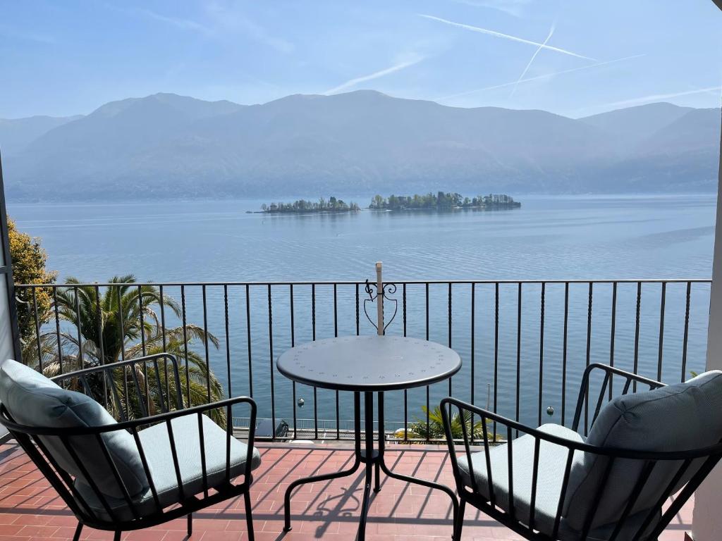 una mesa y sillas en un balcón con vistas al agua en Residenza Bettina BnB & Ferienwohnungen, en Ronco sopra Ascona