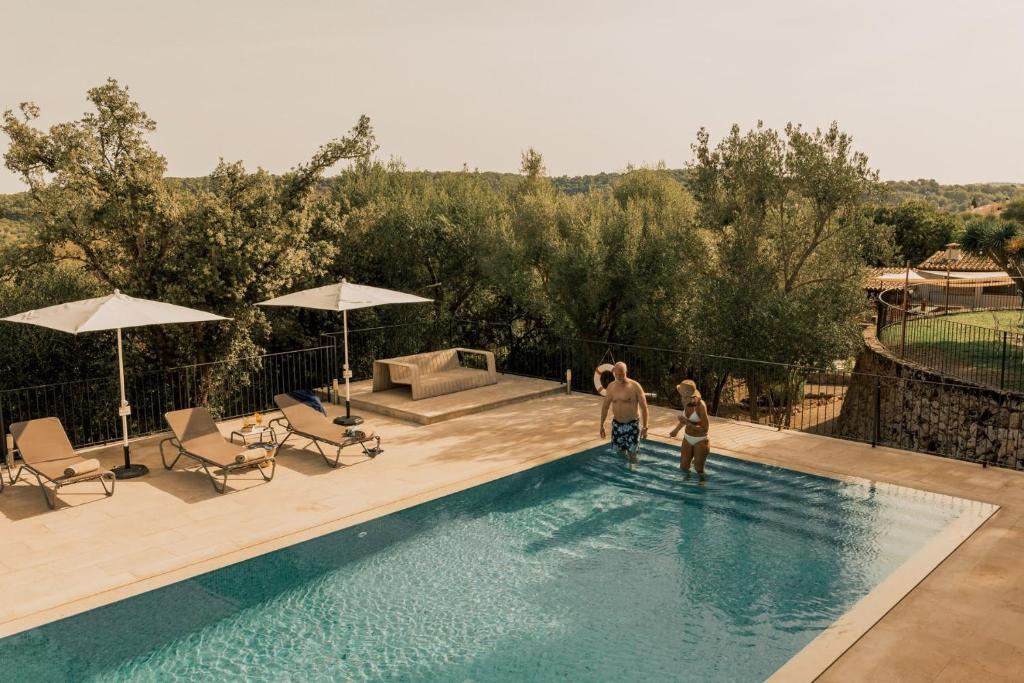 two people are standing in a swimming pool at Cal Secretari Vell - Turismo de Interior in La Cabaneta