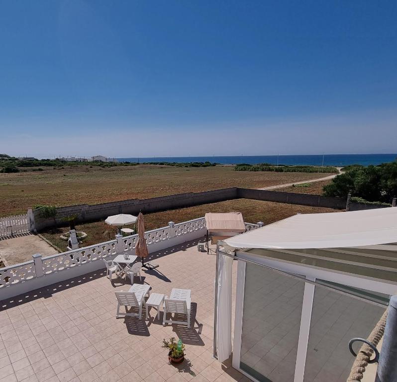 une terrasse avec des chaises et des parasols et l'océan dans l'établissement Le case di Pat - Casa Marea, à San Pietro in Bevagna