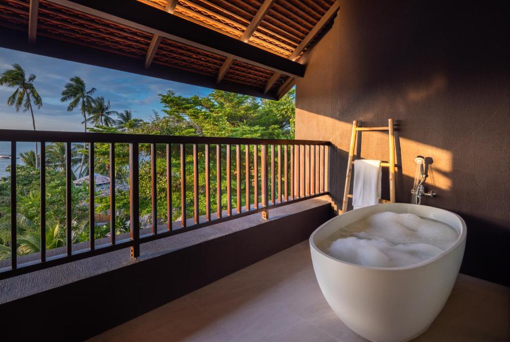 a bath tub on a balcony with a view of the ocean at The Culture Samui in Bangrak Beach