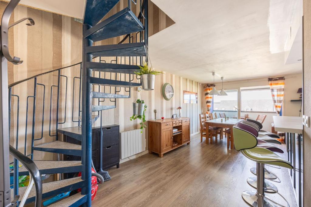 - un escalier en colimaçon dans une chambre avec une table et des chaises dans l'établissement Le Cockpit, à Courseulles-sur-Mer