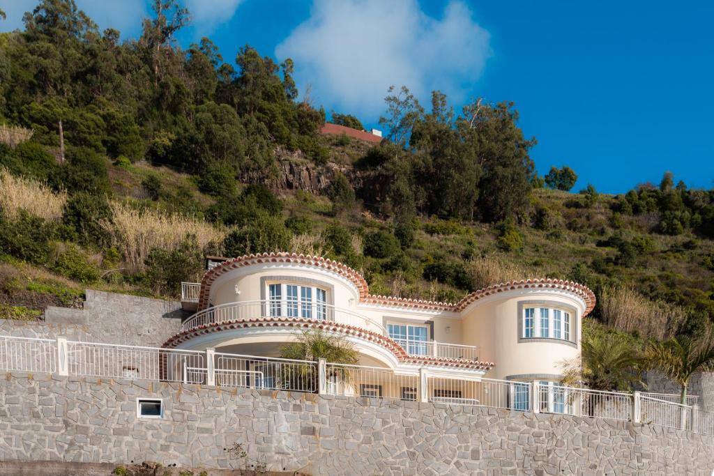 ein großes weißes Haus auf einem Hügel in der Unterkunft Sunnyside Villa in Arco da Calheta