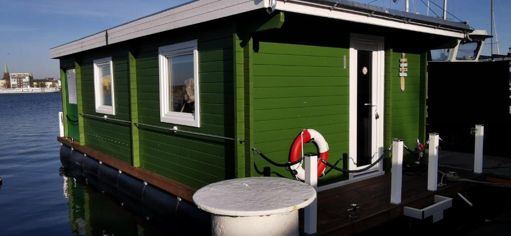 ein grünes Haus auf einem Boot auf dem Wasser in der Unterkunft Hausboot Wilhelmshaven - Traum Unterkunft an der Jade in Wilhelmshaven
