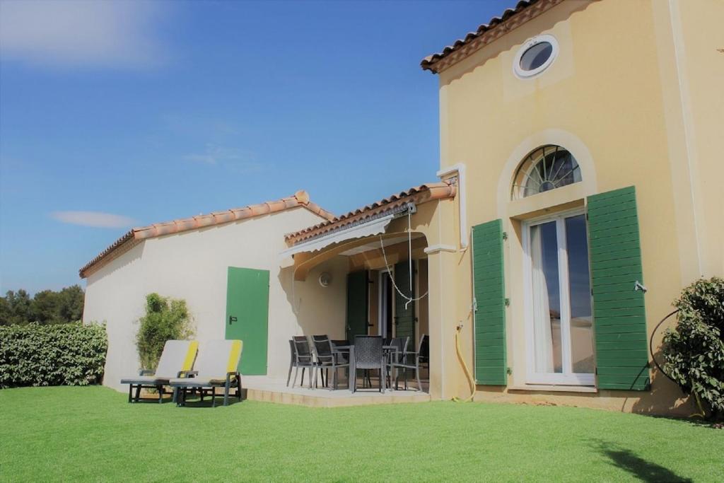 une maison avec une cour dotée de chaises et d'une terrasse dans l'établissement Rose Villa Saint Thomas Golf Course, Beziers, à Béziers