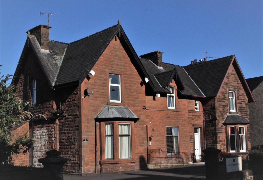 een groot bakstenen huis met een zwart dak bij Glenlossie Guest House in Dumfries