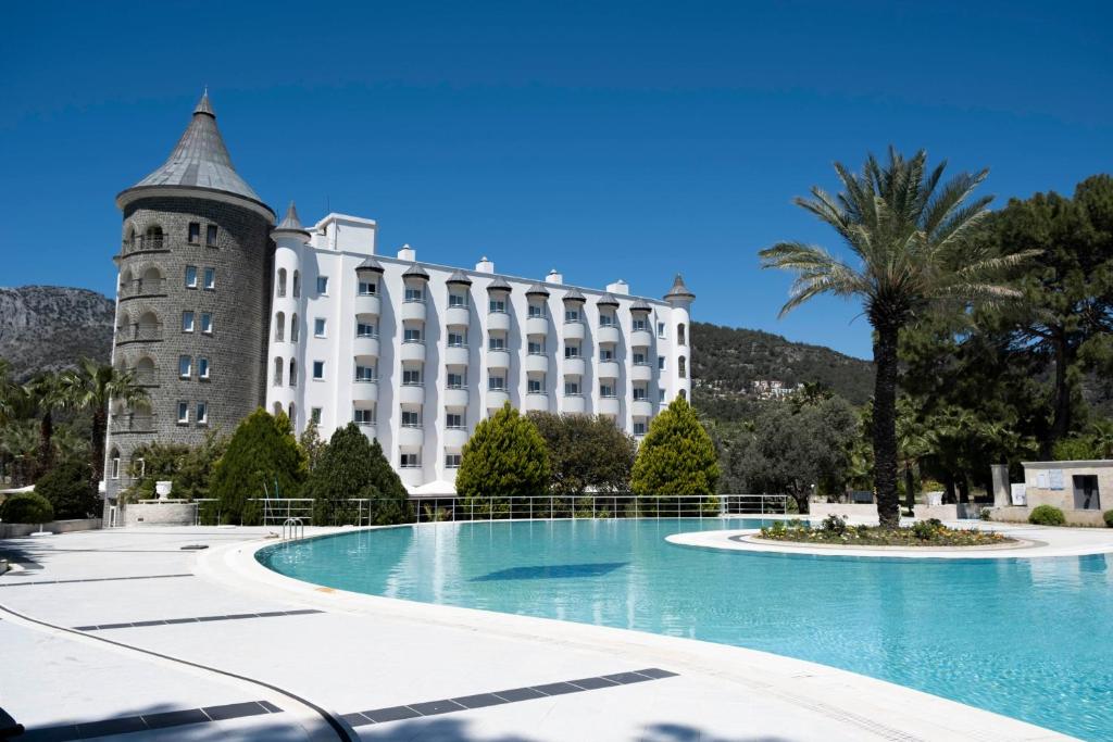 un hotel con una palmera y un edificio en X Life Hotel Sarıgerme 15 - Adult Hotel, en Sarigerme