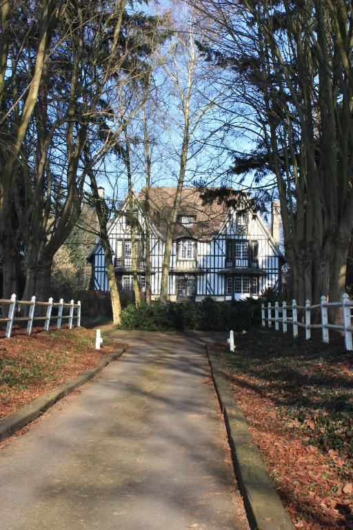une route devant une maison avec une clôture blanche dans l'établissement Le Prieuré Boutefol, à Surville