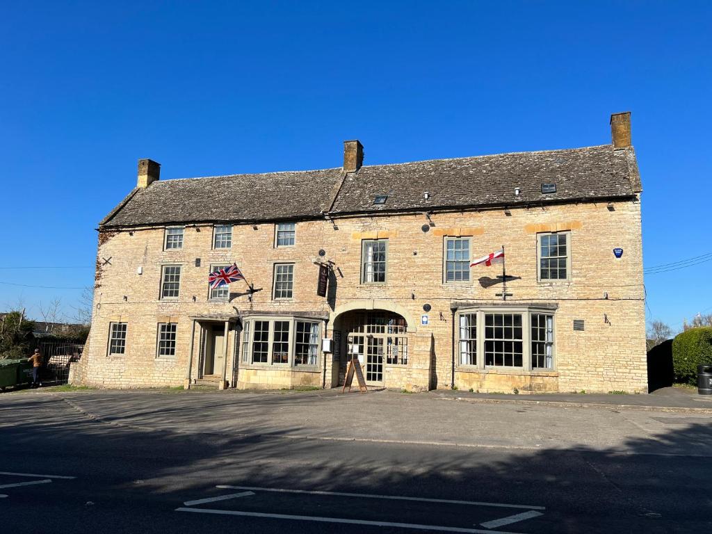 un gran edificio de ladrillo con dos banderas. en The Halford Bridge Inn en Shipston on Stour