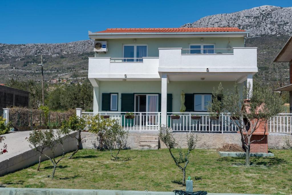 ein weißes Haus mit einem Hügel im Hintergrund in der Unterkunft Apartment Tanja in Kaštela