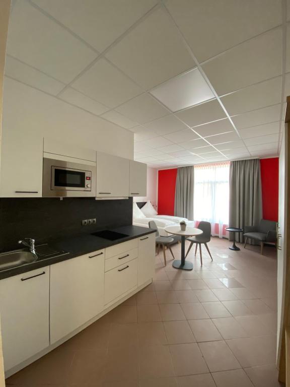 a kitchen with white cabinets and a table in a room at Nord-Ries Apartments in Fremdingen