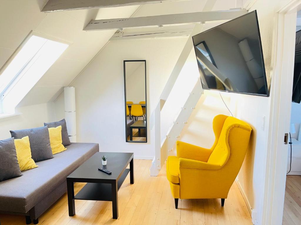 a living room with a couch and a yellow chair at aday - Reberbansgade Apartment Suite in Aalborg