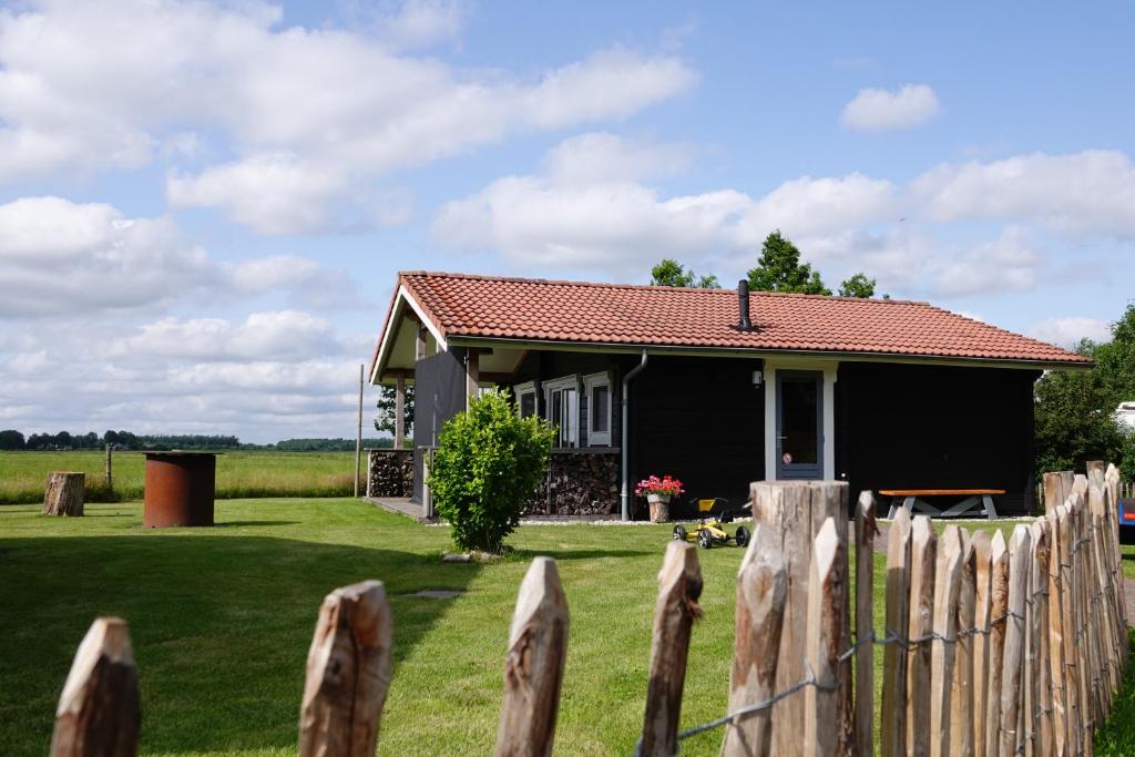 una casa negra con una valla delante en Charme camping Vorrelveen, en Beilen
