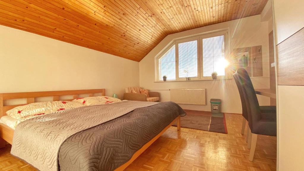 a bedroom with a bed and a chair and a window at Relax Villa Tatry - Wifi/TV, BBQ, Billiard in Nová Lesná