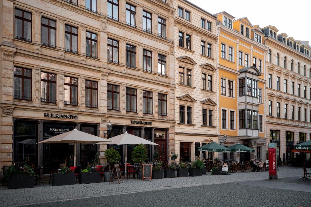 ein großes Gebäude mit Tischen und Sonnenschirmen davor in der Unterkunft Townhouse Leipzig in Leipzig