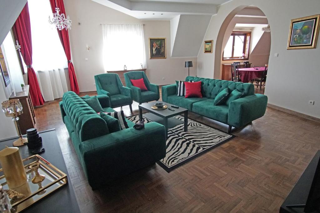 un soggiorno con divani verdi e cuscini rossi di Marija Delux 3 a Srbobran