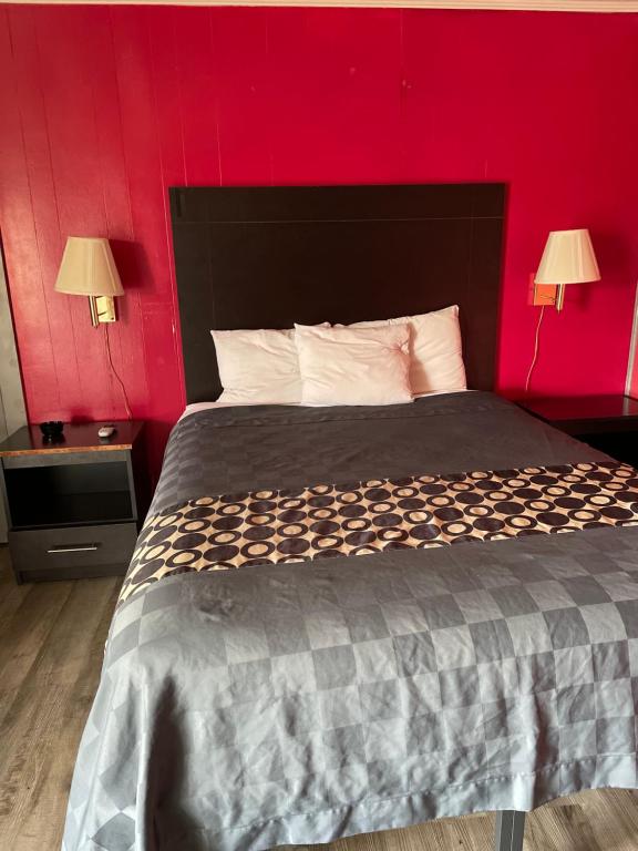a bedroom with a large bed with a red wall at Budget Inn in Monroeville