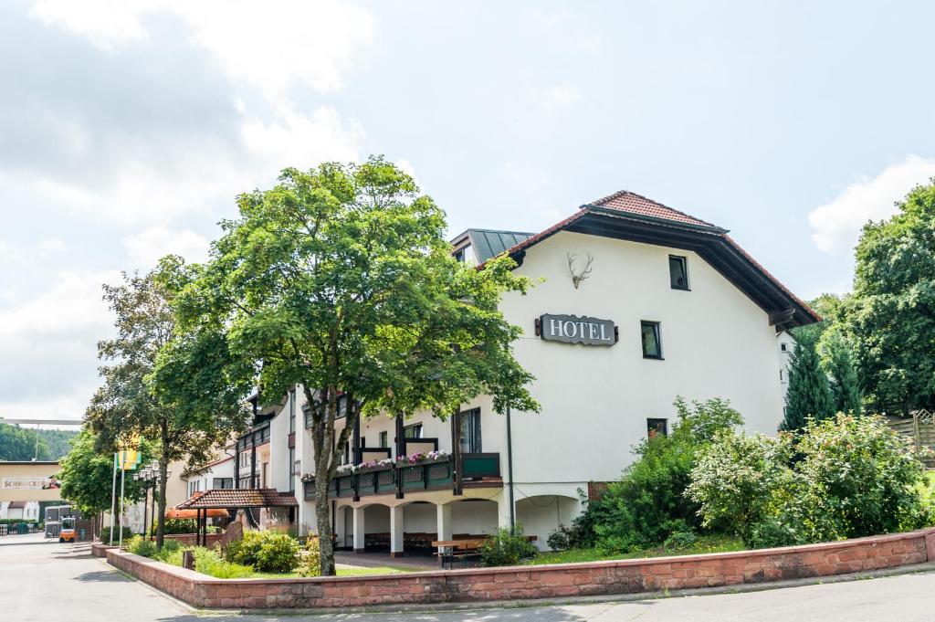 un bâtiment blanc avec un arbre devant lui dans l'établissement Hotelgasthof Schmucker, à Mossautal