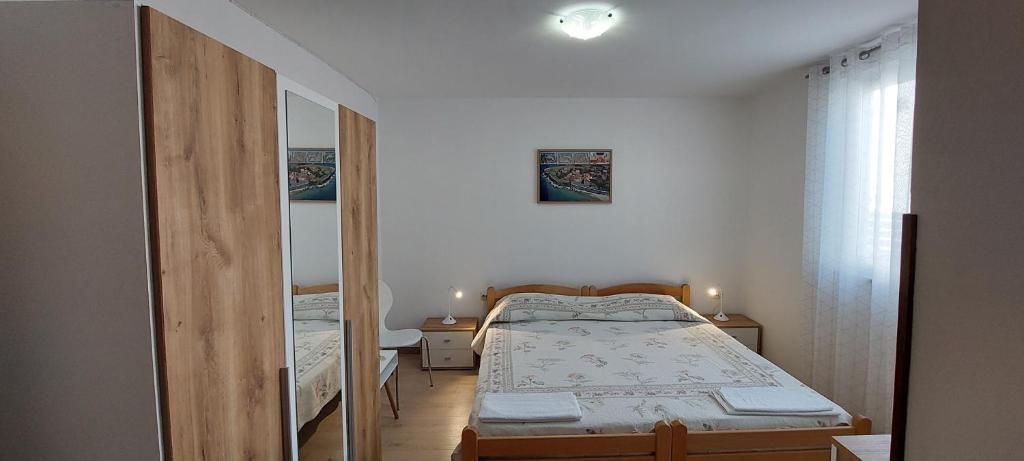 a small bedroom with a bed and a mirror at Room Eta in Cres