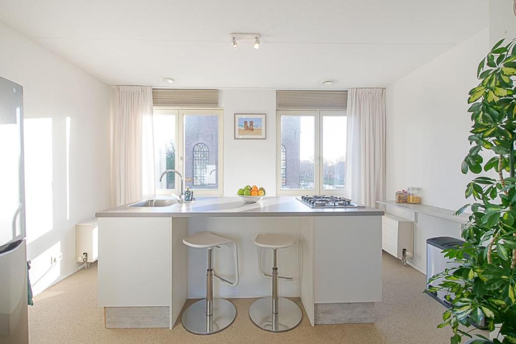 a kitchen with a sink and a counter with stools at De Jutter in Den Helder