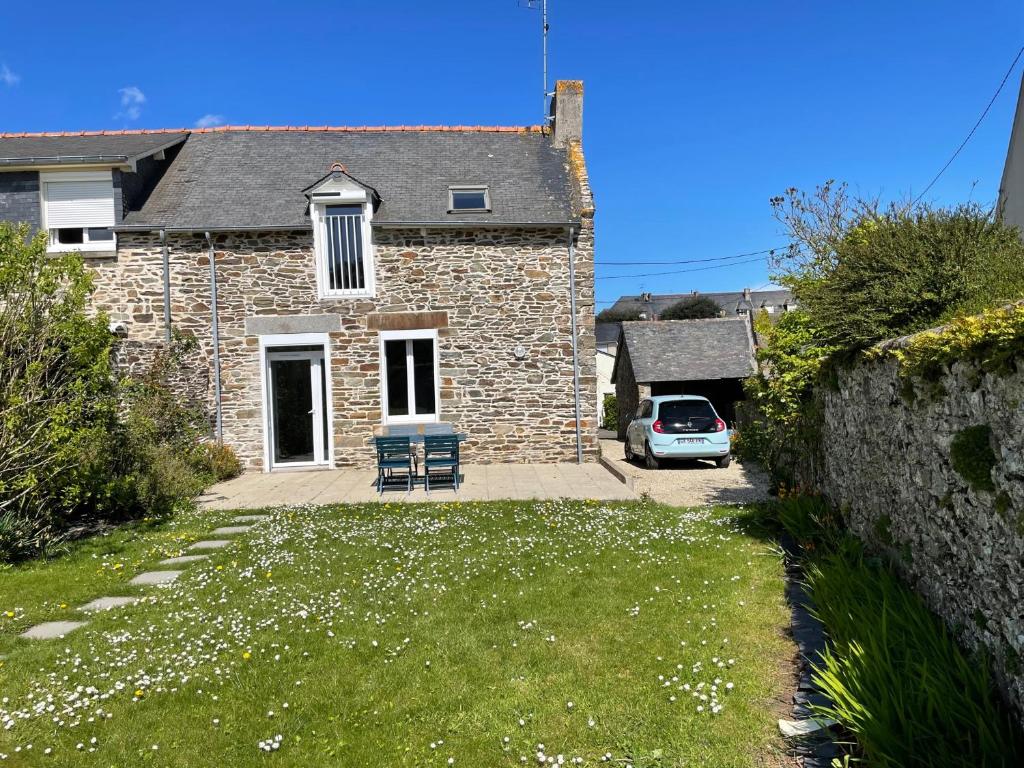 a brick house with a car parked in the driveway at Gites La Ville Pain in Cancale