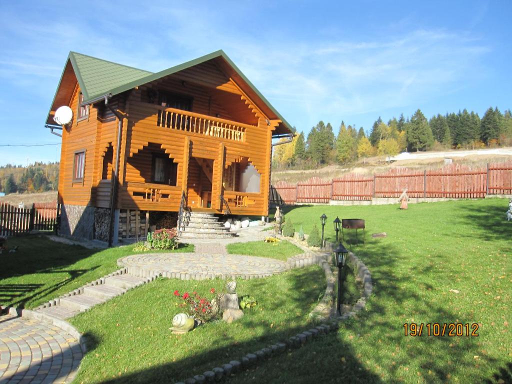 uma grande casa de madeira com um quintal e uma cerca em Вілла Олекси em Skhidnitsa