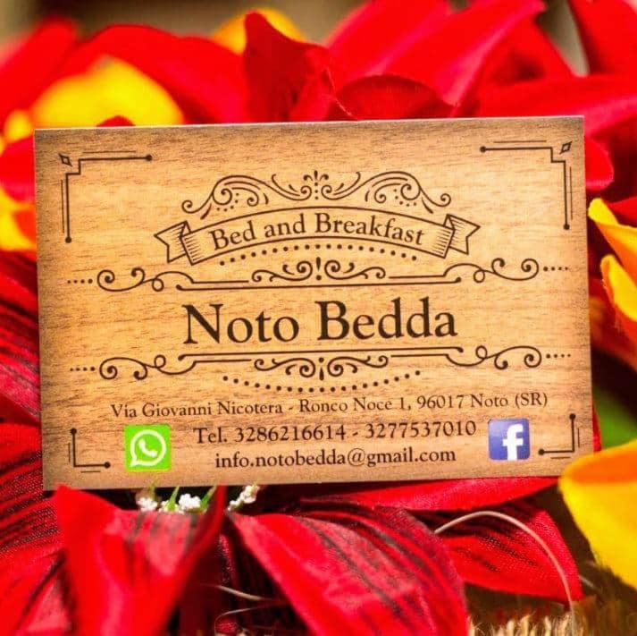 una señal sentada encima de un montón de flores en Noto Bedda Bed&Breakfast, en Noto