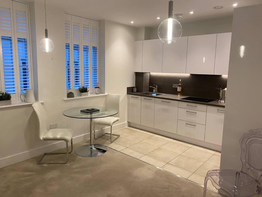 a kitchen with white cabinets and a table and chairs at UNRIVALLED LOCATION FIVE STAR WORCESTER APARTMENT in Worcester