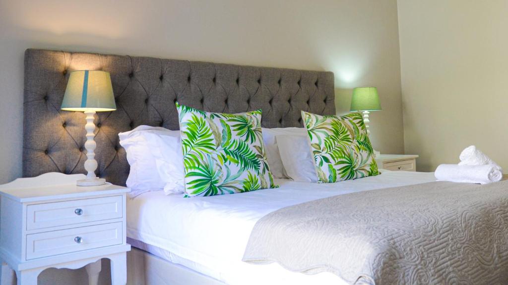 1 dormitorio con 1 cama grande con almohadas verdes en Olive Tree, en Paarl