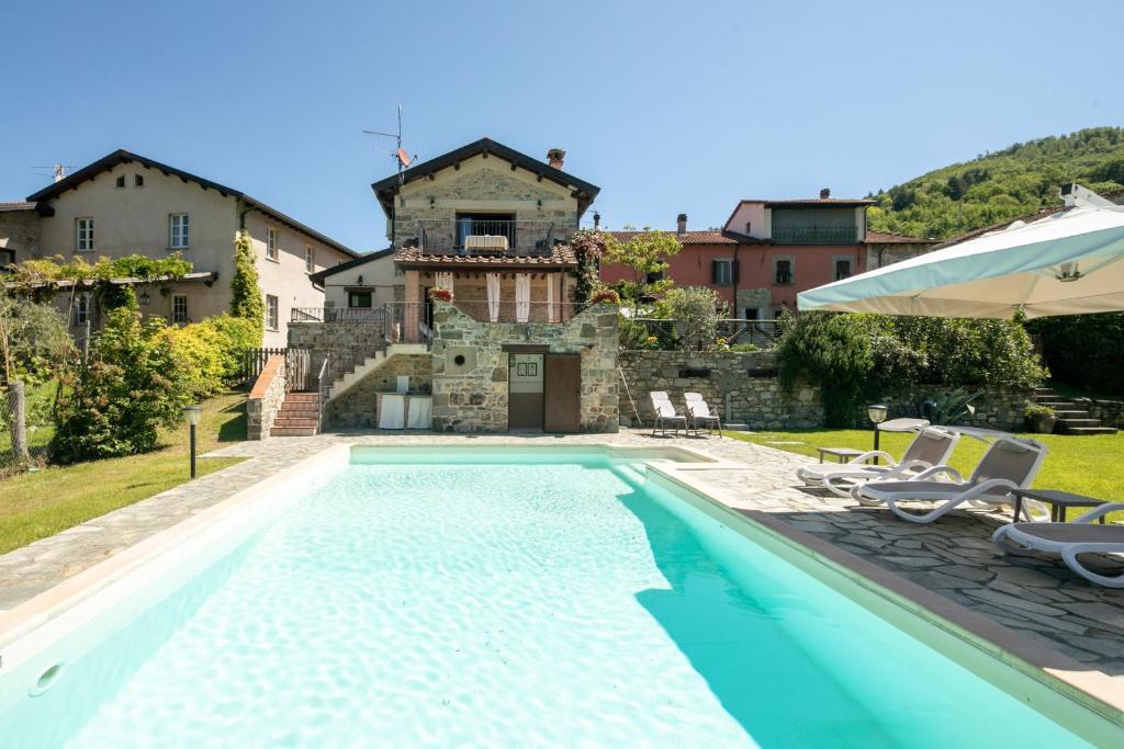 einem Pool vor einem Gebäude mit einem Haus in der Unterkunft Country house with pool and outbuilding Fivizzano by VacaVilla in Terenzano