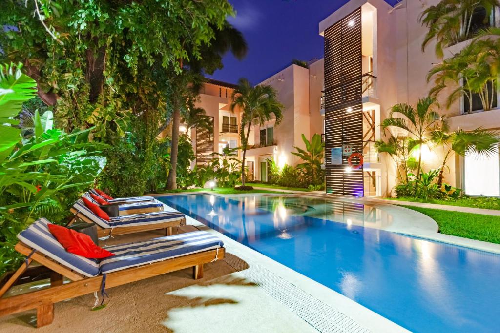 a swimming pool with two lounge chairs next to a building at Via Tendenza Condos in Playa del Carmen