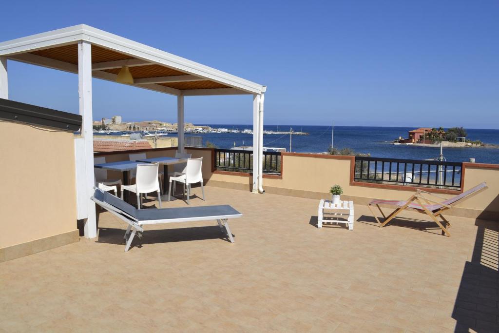 een patio met een tafel en stoelen en de oceaan bij Marzamemi Vacanze in Marzamemi