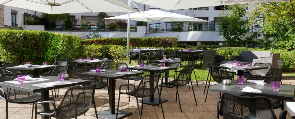 a group of tables with chairs and umbrellas at Novotel Paris Sud Porte de Charenton in Charenton-le-Pont
