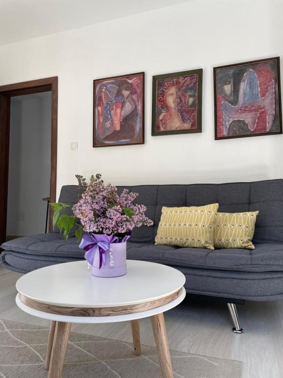 uma sala de estar com um sofá e uma mesa com flores em Rebus Apartments em Sandanski