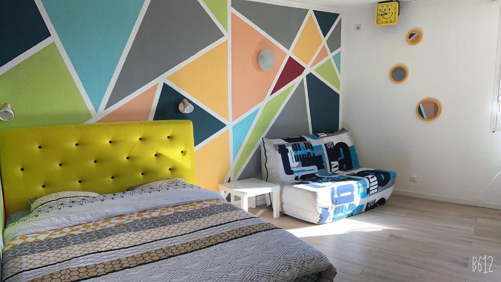 a bedroom with a bed and a colorful wall at Appartement Futuroscope-E' in Chasseneuil-du-Poitou