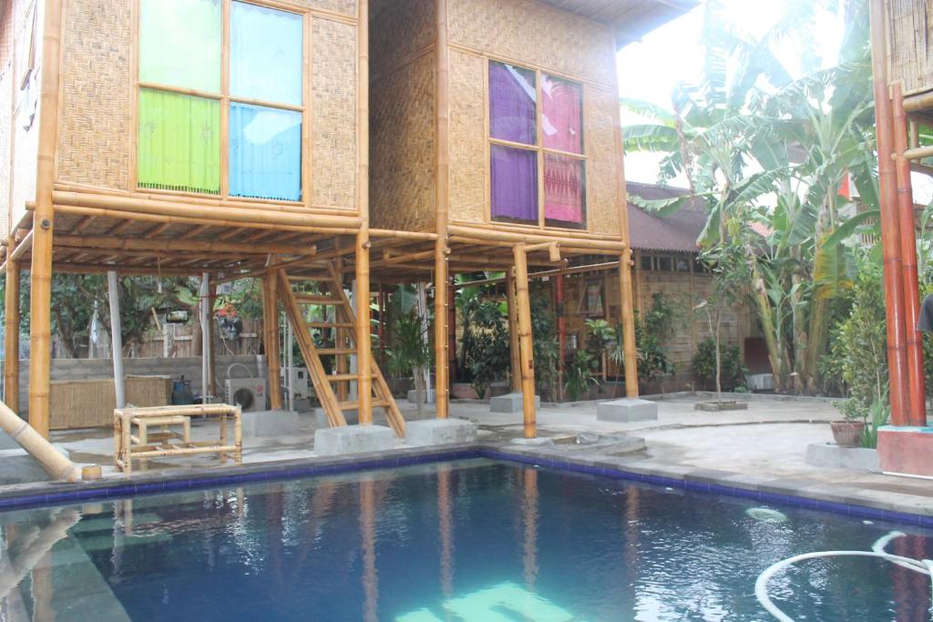 a building with stained glass windows next to a swimming pool at Little Woodstock Homestay in Gili Trawangan