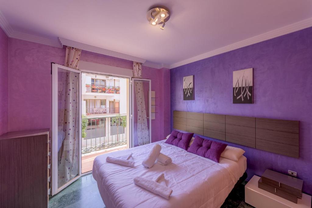 una camera viola con un grande letto e una finestra di Apartamento Céntrico Sibarys-3 dormitorios a Nerja