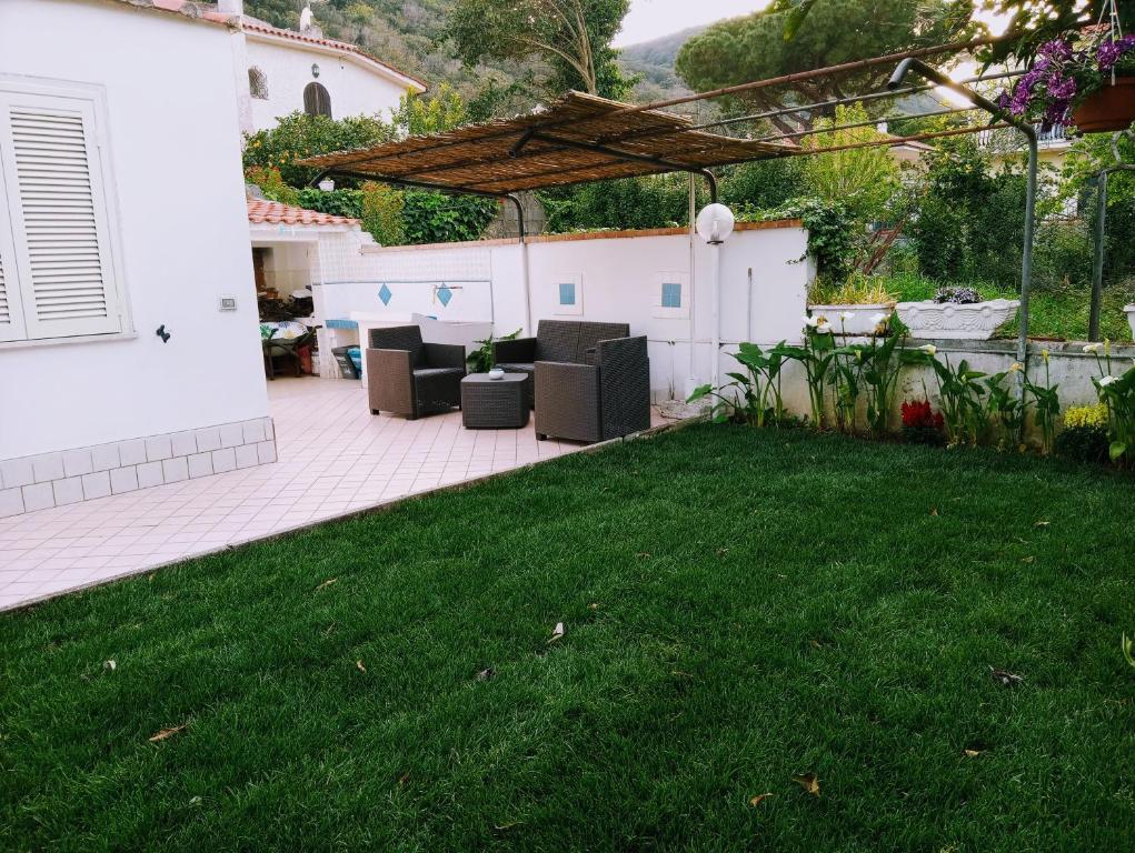 a patio with chairs and a grass yard at Villino Via Sabaudia 39 in San Felice Circeo