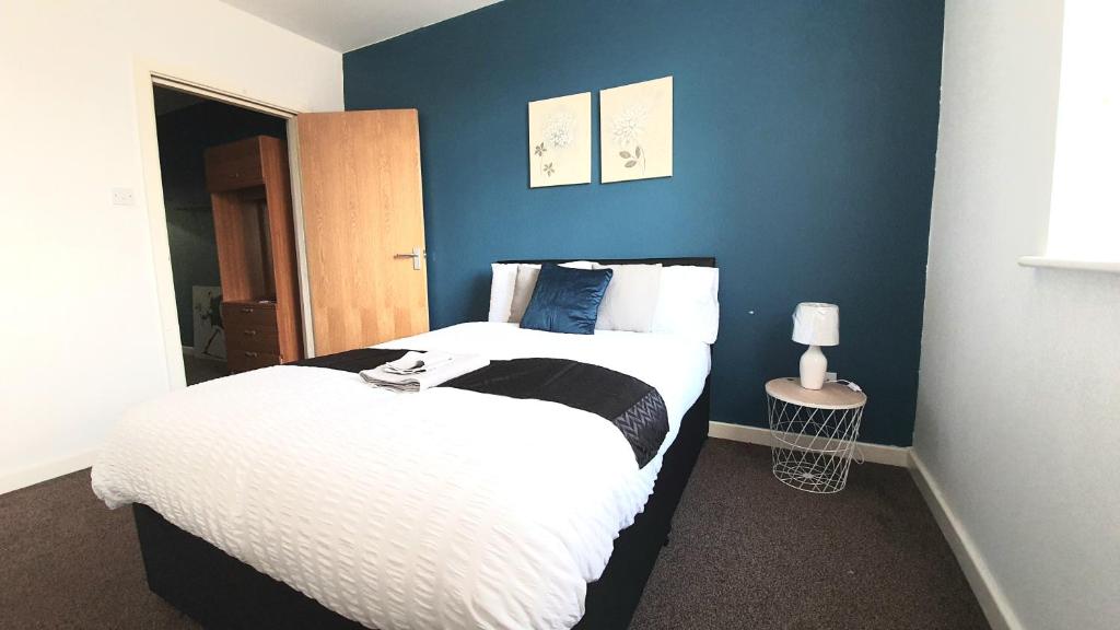 a bedroom with a bed and a blue wall at Salford Ark Comfort Stays near Salford Royal and Trafford Centre in Manchester