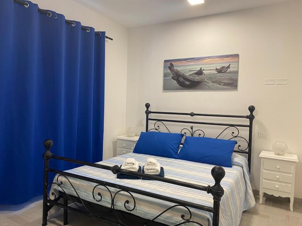 a bedroom with blue curtains and a bed with shoes on it at B&B La Perla in Vasto